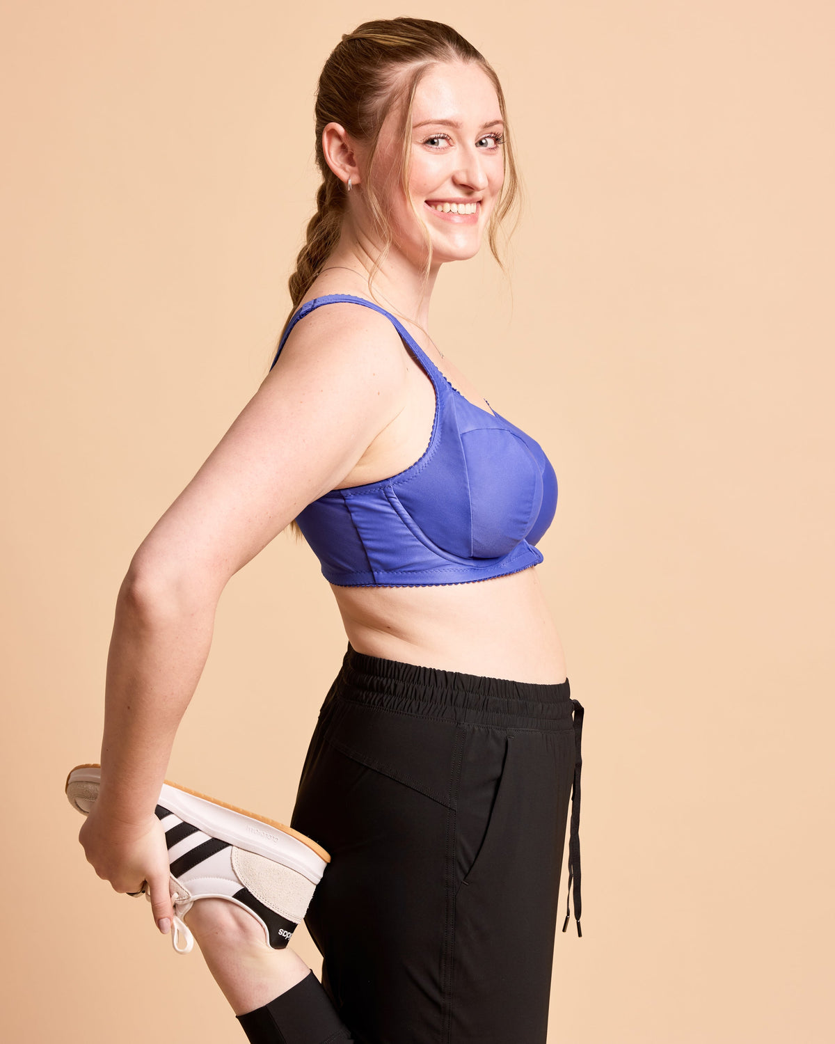 Cashmerette Somerville Sports Bra PDF sewing pattern, woman wearing a blue sports bra and black leggings, holding white sneakers