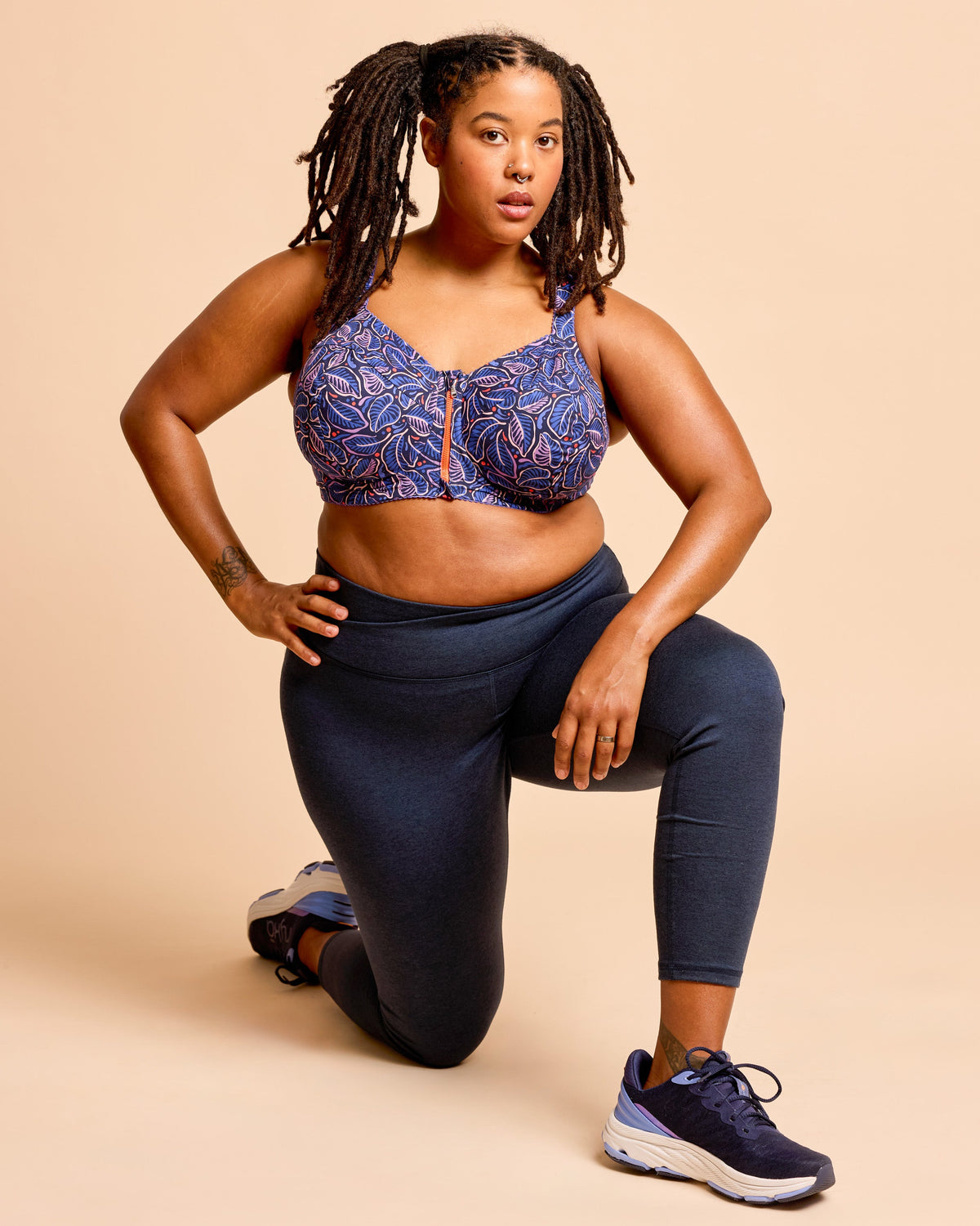 Cashmerette Somerville Sports Bra PDF sewing pattern, woman wearing a blue patterned sports bra and navy leggings, kneeling pose